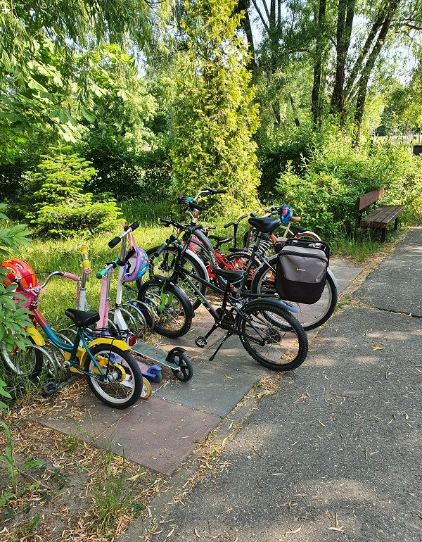 dziecięce rowerki i rower stojące przy stojaku na rowery