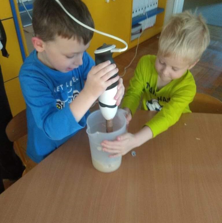 Chłopiec trzyma blender, drugi chłopiec trzyma kubek