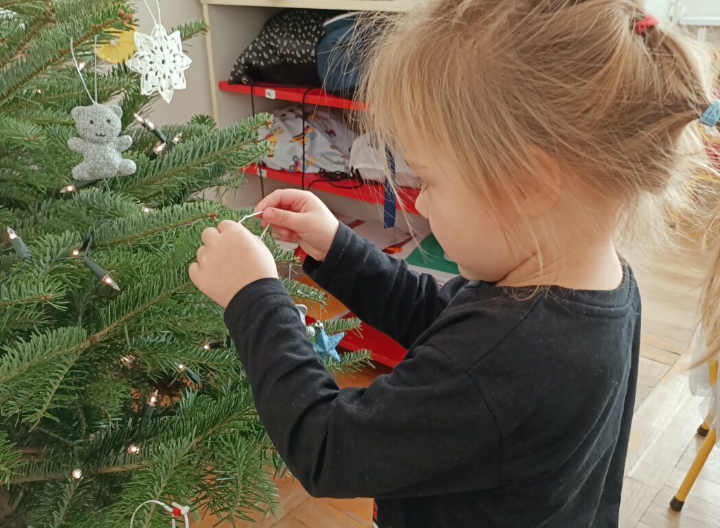 Dziewczynka wiesza na choince ozdobę