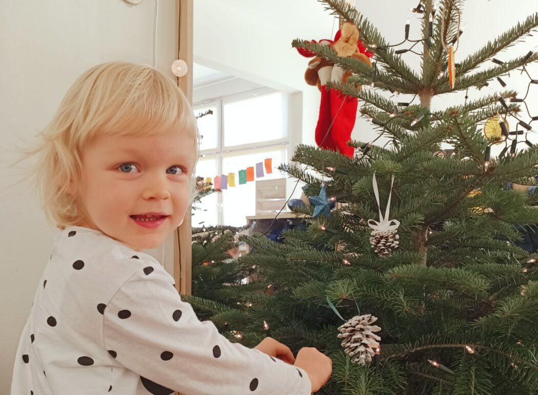 Uśmiechnięta dziewczynka wiesza bombkę na choince