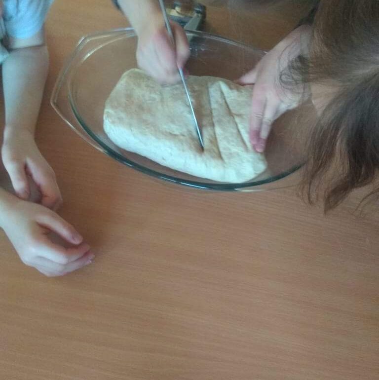 rączki dzieci kroją ciasto