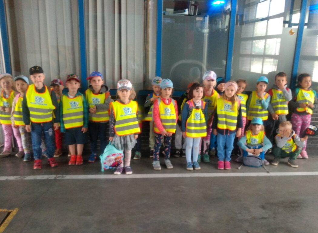 dzieci stoją w szeregu w odblaskowych kamizelkach