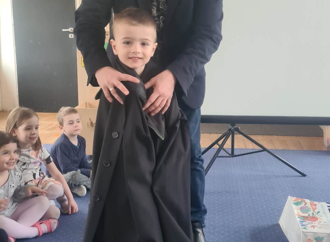 chłopiec w todze a za nim mężczyzna zapinający togę dzięcku