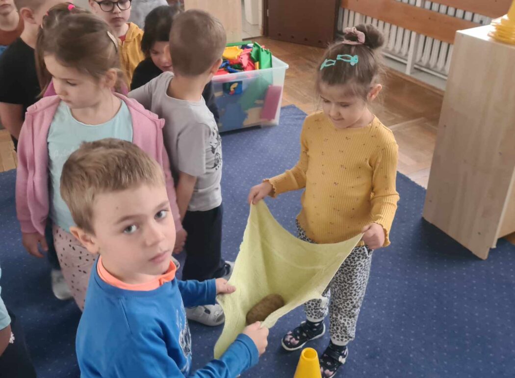 na chustce dwoje dzieci niesie ziemniaka