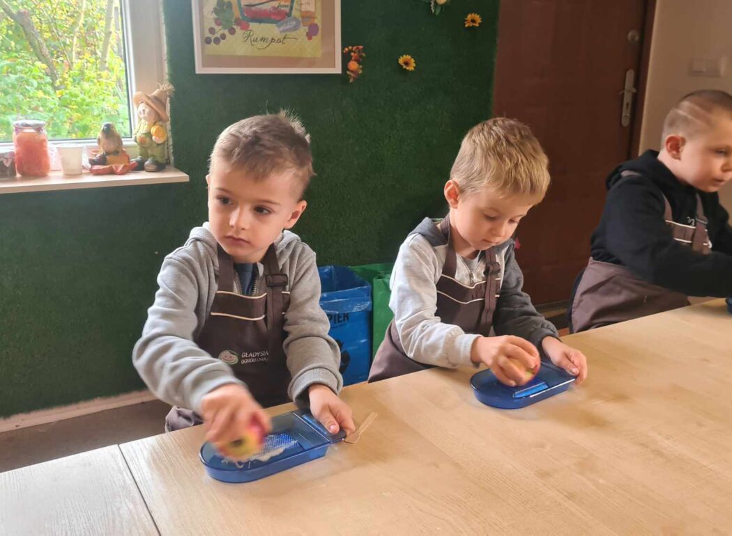 dzieci trą jabłka na tarce