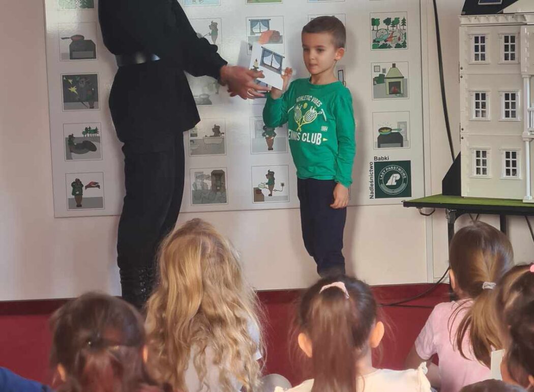 dzieci spoglądają na panią strażaczkę i chłopca w zielonej bluzie