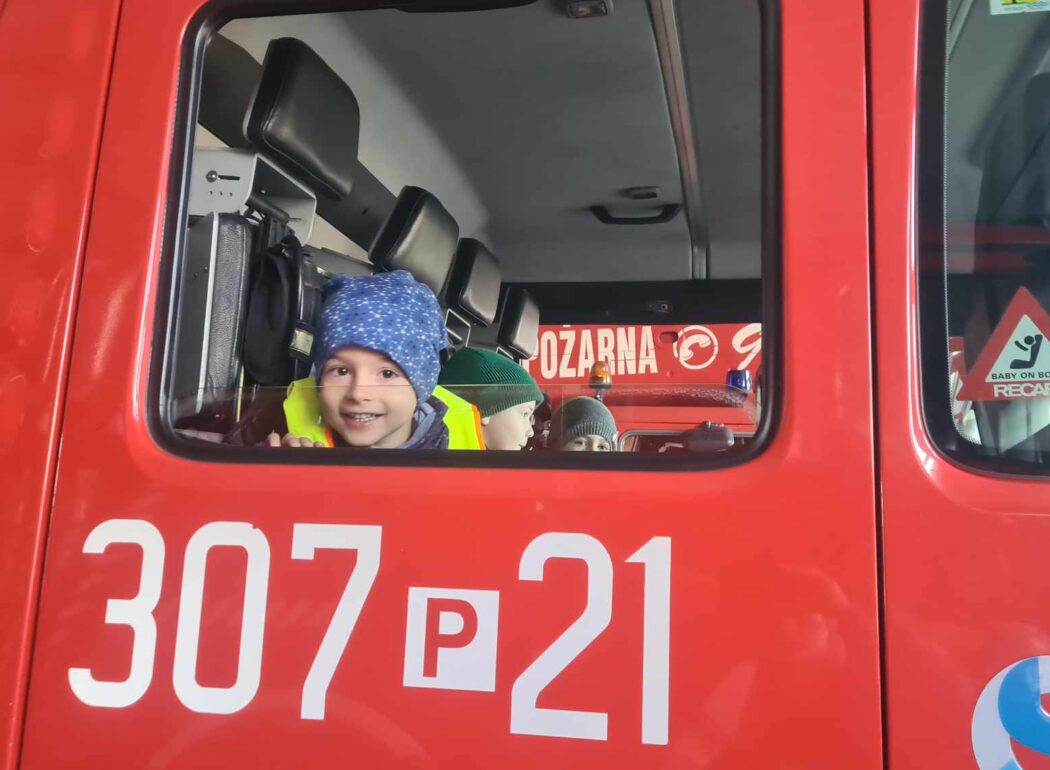 przez okno wozu strażackiego wygląda chłopiec