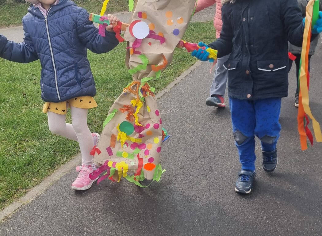 uśmiechnięte dzieci idą trzymając marzannę
